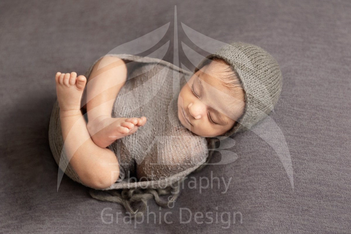 Close up of swaddled sleeping newborn baby wearing grey knit bonnet, professional newborn photography by Windsor Ontario photographer Mariam Cheaitou Bazzi